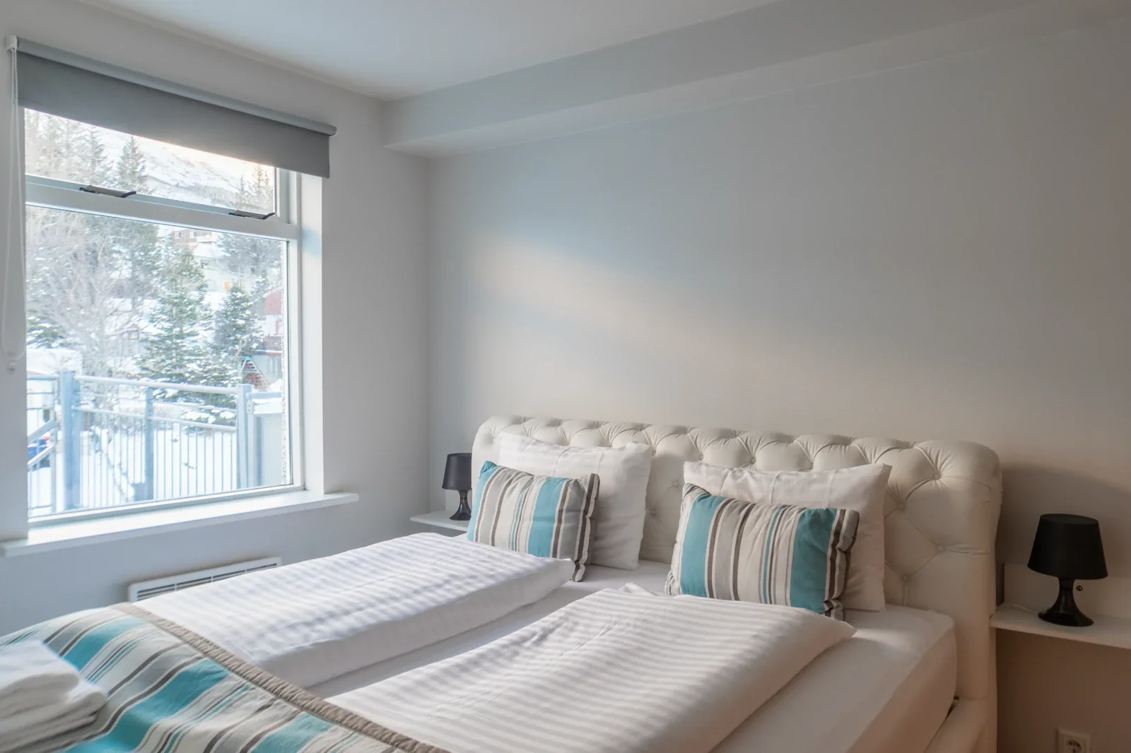 White upholstered bed beside the window in a Hildibrand apartment