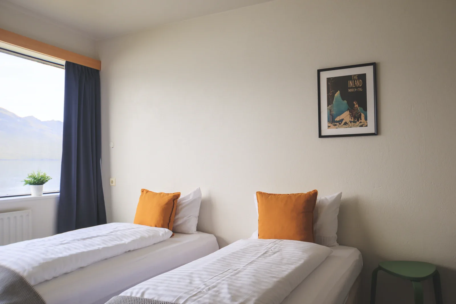 Twin beds with mustard cushions and a fjord view at The Cliff