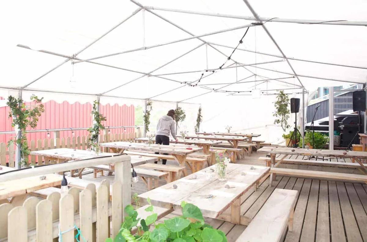 Wooden tables laid for a celebration beneath a white marquee.