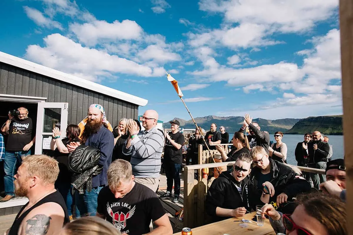 Guests gathered on a sunny waterfront terrace with mountains across the fjord.