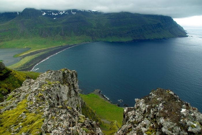 A rocky viewpoint above a bay and green coastal cliffs